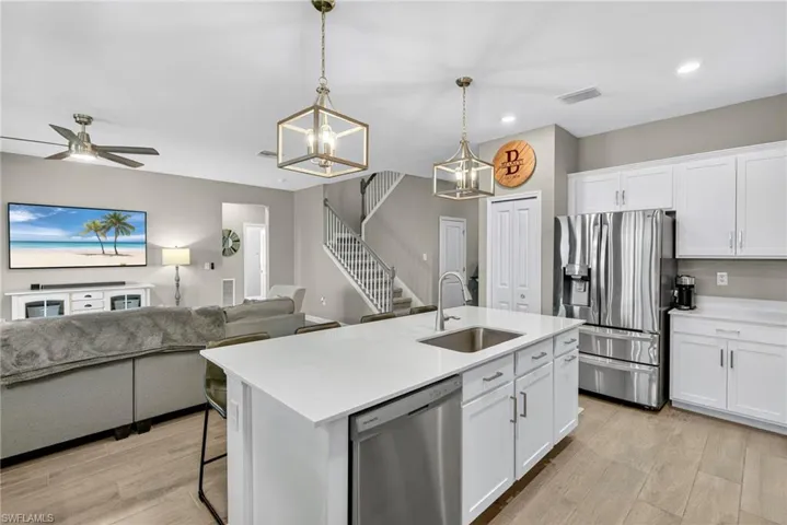 Kitchen featuring stainless steel appliances, light wood-type flooring, white cabinetry, hanging light fixtures, and recessed lighting