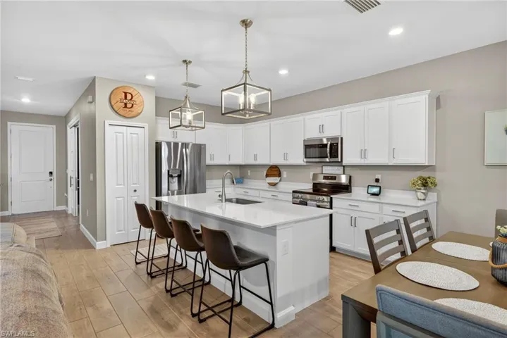 Kitchen featuring stainless steel appliances, a center island with sink, pendant lighting, light wood finished floors, and recessed lighting