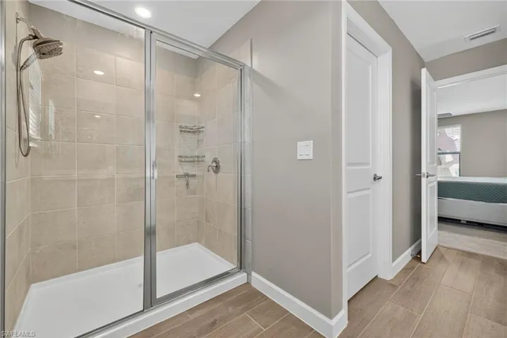 Bathroom with connected bathroom, wood tiled floors, and a shower stall