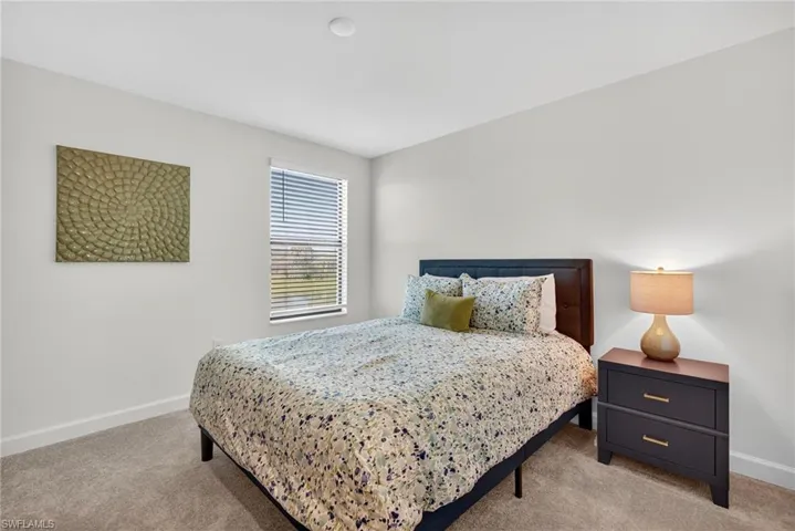Bedroom featuring light carpet and baseboards