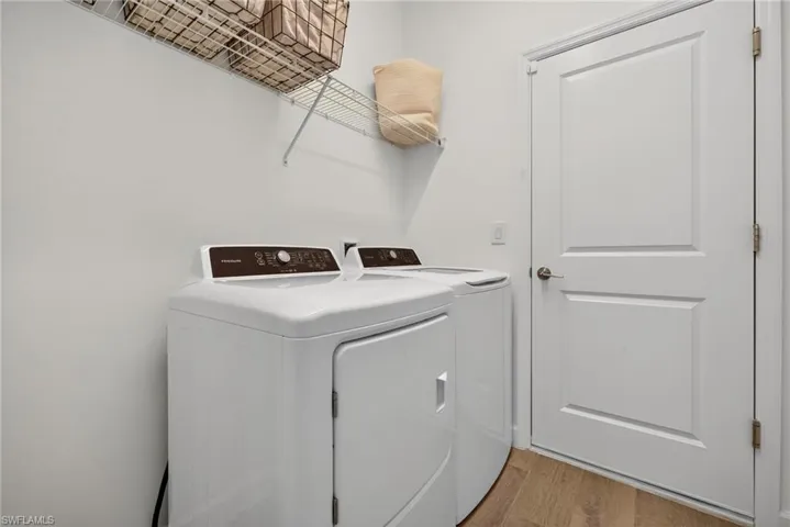Laundry area with light wood-style flooring and washing machine and clothes dryer