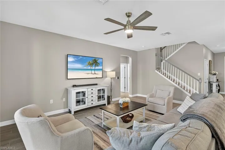 Living room with wood finished floors, stairway, and a ceiling fan