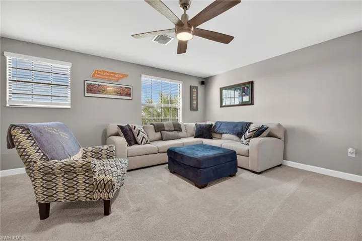 Carpeted living room featuring baseboards and ceiling fan