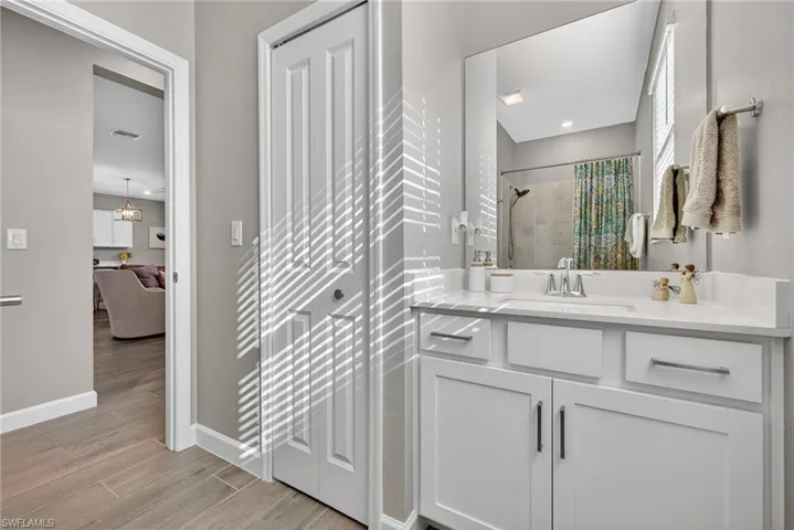 Full bathroom featuring vanity, a tile shower, and light wood-style floors
