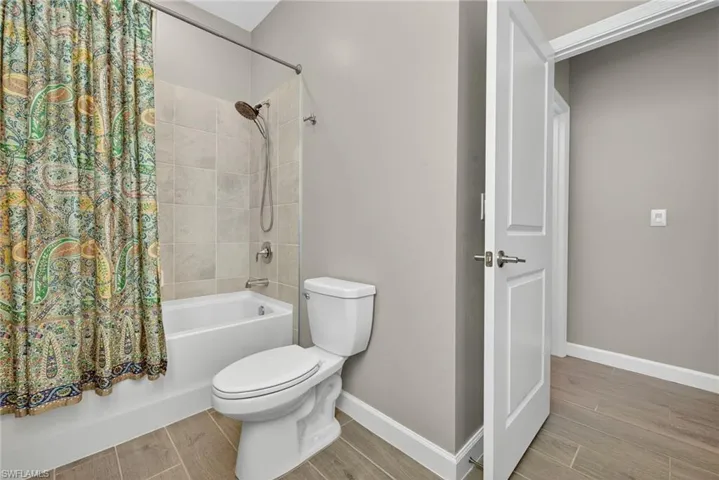Bathroom featuring wood finish floors and shower / bath combo with shower curtain