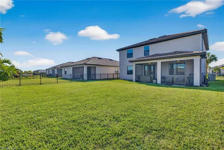 Rear view of house with a fenced backyard and a sunroom