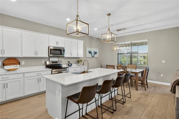 Kitchen with recessed lighting, stainless steel appliances, decorative light fixtures, white cabinetry, and light wood finished floors
