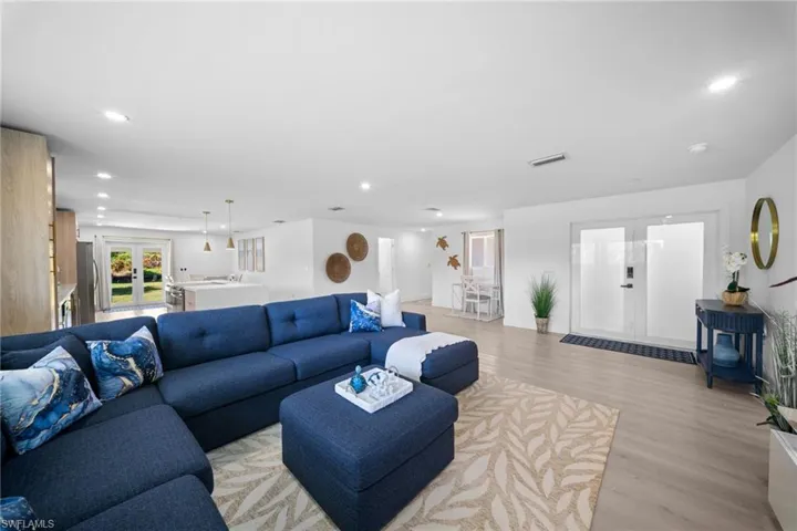 Open-concept interior with wood-finish flooring, recessed lighting, and double-glass entry doors