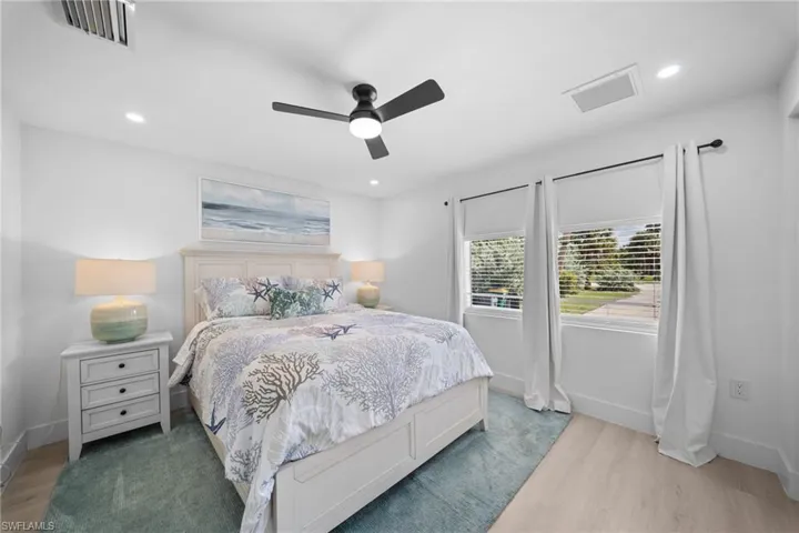 1st guest bedroom Neutral interior space featuring wood-finish flooring, a modern black ceiling fan with integrated lighting, recessed lighting, and expansive windows