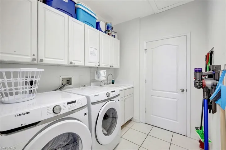 Laundry room with a sink, cabinet space, light tile patterned floors, and washer and dryer