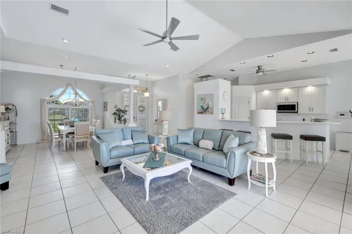 Living area with light tile patterned floors, ceiling fan, and lofted ceiling