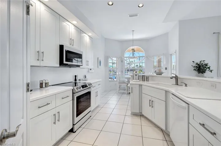 Kitchen featuring light solid-surface countertops, stainless steel and white appliances, and recessed lighting