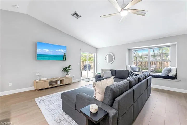 Living area with vaulted ceiling, ceiling fan, and light wood-style flooring