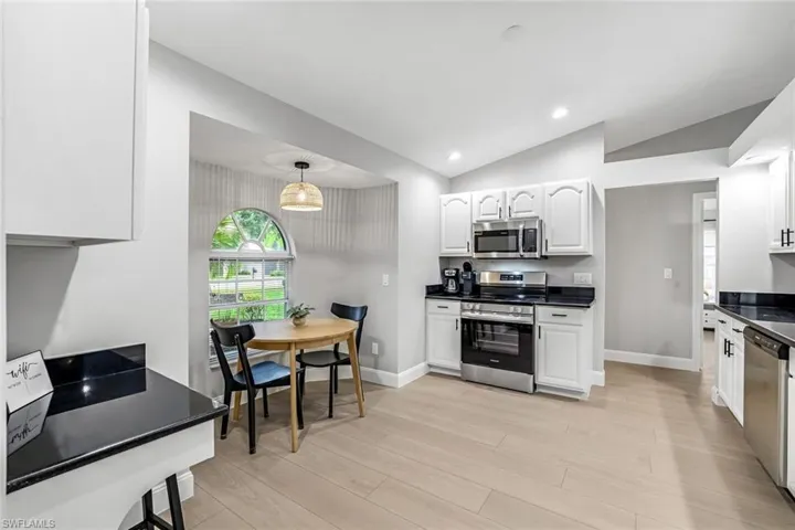 Kitchen with appliances with stainless steel finishes, vaulted ceiling, white cabinets, light wood-style flooring, and recessed lighting