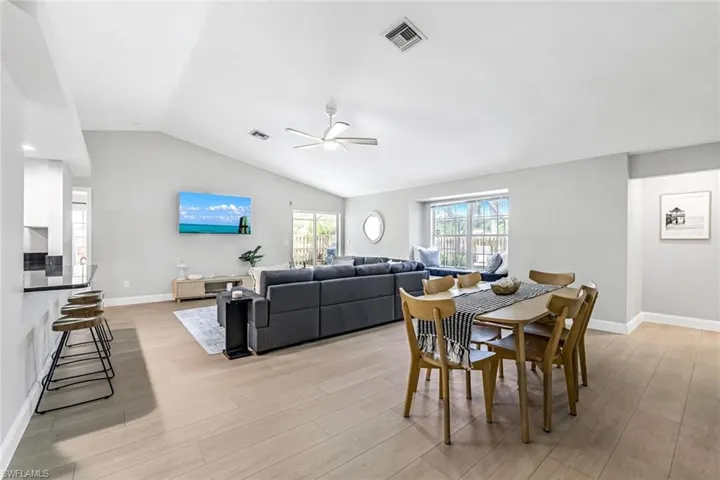 Dining space with vaulted ceiling, light wood finished floors, and a ceiling fan