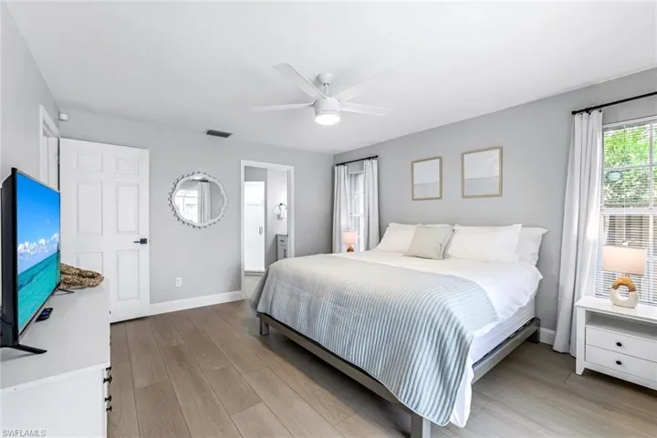 Bedroom featuring light wood-style flooring, ensuite bathroom, and ceiling fan