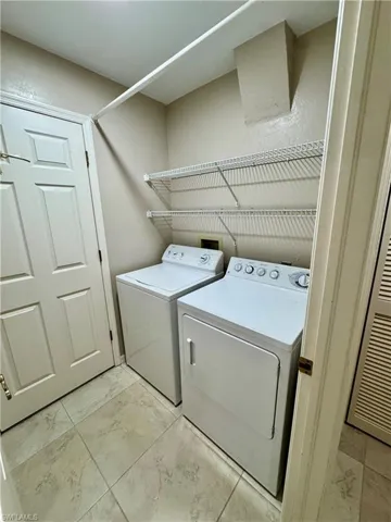 Washroom featuring light marble finish floors and washing machine and dryer