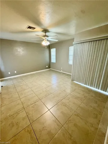 Empty room with a textured ceiling, a ceiling fan, and light tile patterned floors