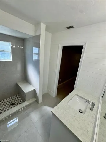 Full bathroom featuring vanity, light tile patterned flooring, a stall shower, and a textured ceiling