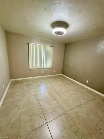 Empty room with a textured ceiling and light tile patterned flooring