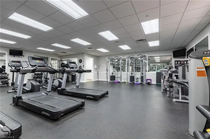 Fitness area with resilient flooring, multiple treadmills, strength training equipment, and reflective wall panels