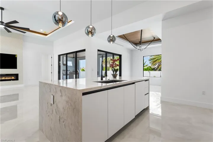 Large FARMHOUSE SINK w/ black faucet, WATERFALL KITCHEN ISLAND & UNDER-CABINET LED LIGHTING add MODERN TOUCHES OF SOPHISTICATION.