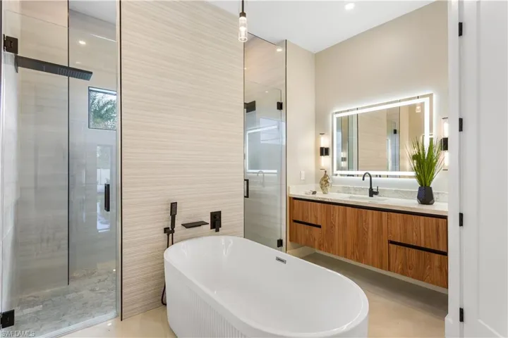 This luxurious master bathroom features a spa-like atmosphere with a soaking tub, walkthrough shower, and elegant finishes. With sleek countertops, custom cabinetry, and high-end fixtures, it's the perfect retreat for relaxation and rejuvenation.