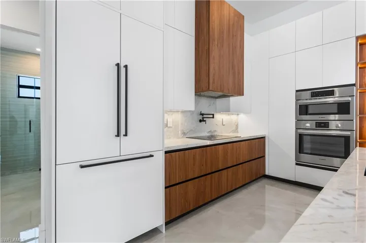 CUSTOM CABINETRY, QUARTZ COUNTERTOPS & FULL BACKSPLASH elevate the space, along w/ HIGH-END APPLIANCES, BOSCH WALL OVEN & MICROWAVE, INDUCTION COOKTOP, MICROWAVE, INTEGRATED DISHWASHWER & DACOR BUILT-IN REFRIGERATOR & FREEZER.