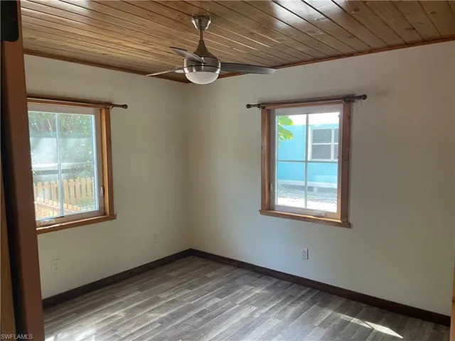 Empty room with wooden ceiling, wood finished floors, a ceiling fan, and healthy amount of natural light