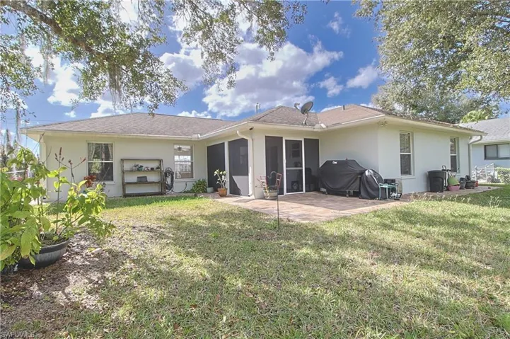 Rear exterior featuring a screened patio, a paver patio area, and a light-colored stucco finish