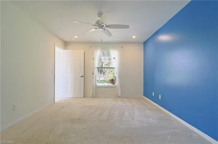 Spacious room featuring neutral carpet flooring, a ceiling fan with integrated lighting, recessed lighting, and a prominent accent wall