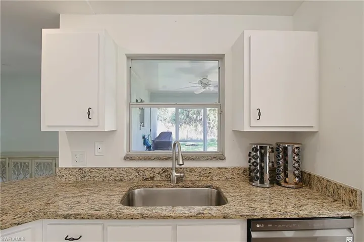 Kitchen sink area featuring a stainless steel undermount sink, granite countertops, and white cabinetry