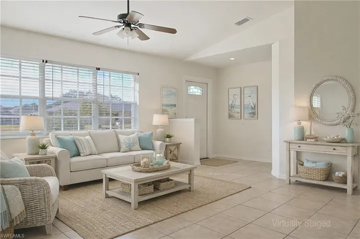 Spacious living area featuring large windows with horizontal blinds, tiled flooring, a ceiling fan with integrated lighting, and neutral wall tones