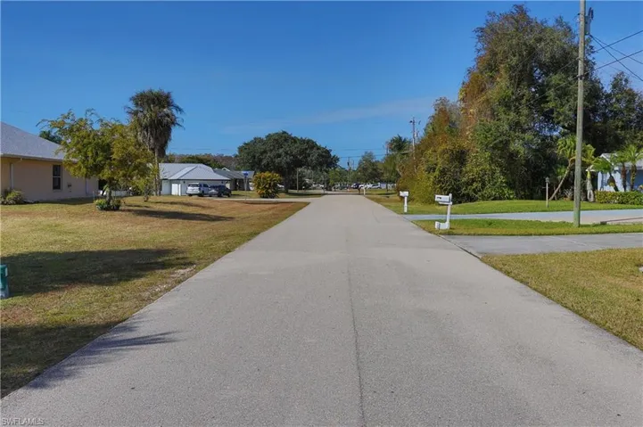 Paved residential street with manicured lawns and mature trees