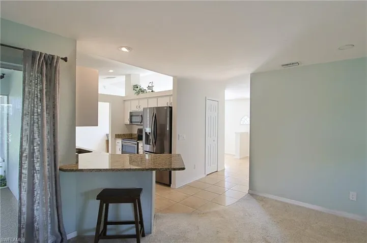 Kitchen pass-through featuring a granite countertop and upper cabinetry