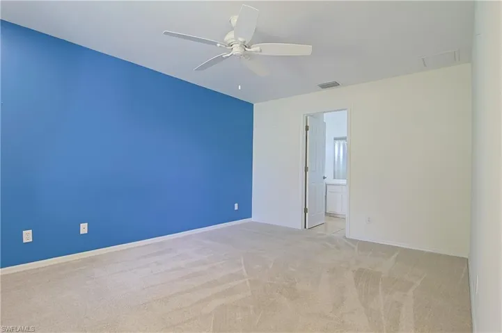 Spacious room with a neutral carpeted floor, light-colored walls, and a contrasting accent wall