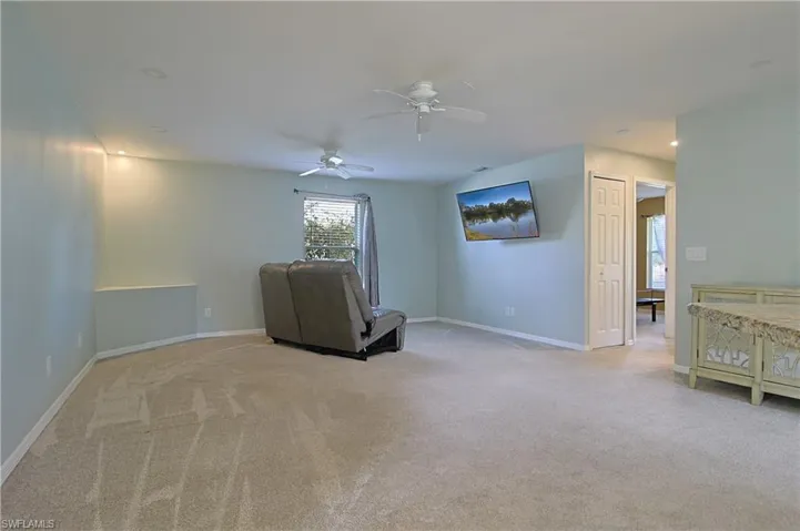 Spacious room featuring neutral carpeting, two ceiling fans with integrated lighting, recessed lighting, and a window with white blinds