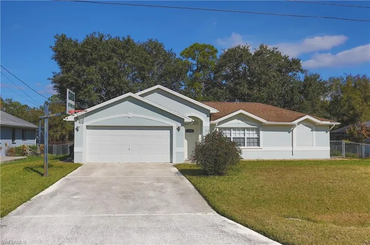 Light blue exterior with white trim, a two-car garage, a concrete driveway, a front lawn, and a light brown shingle roof