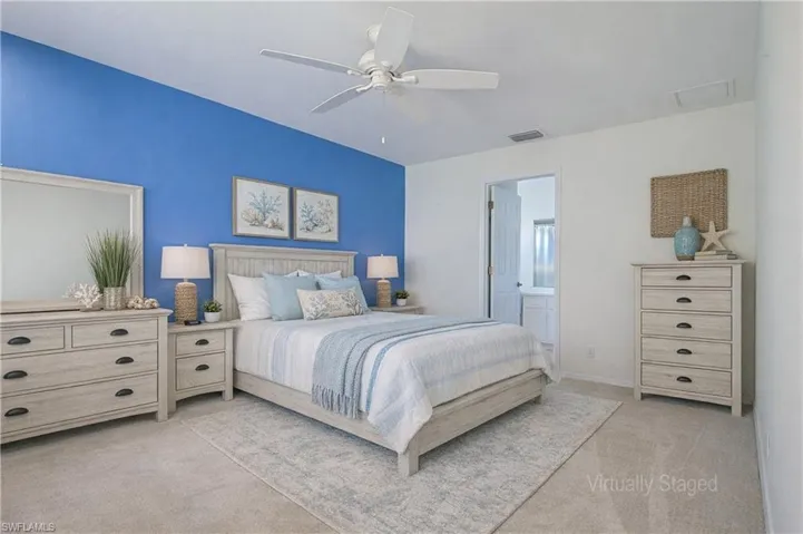 Bedroom featuring a vibrant accent wall, wall-to-wall carpeting, and a ceiling fan