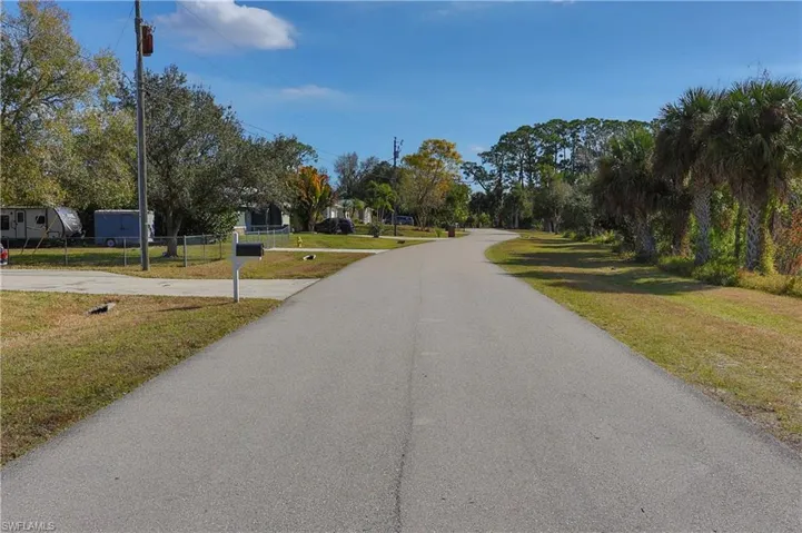Paved road with curbside landscaping and mature trees