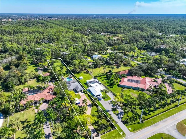 Aerial perspective of suburban area featuring property parcel outlined and a heavily wooded area