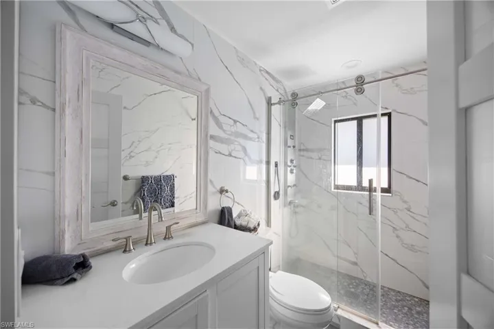 Full bath featuring vanity and a marble finish shower