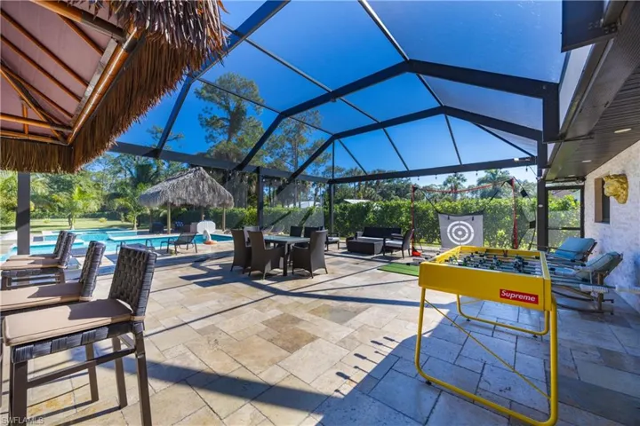 View of patio with glass enclosure, an outdoor pool, and outdoor dining area