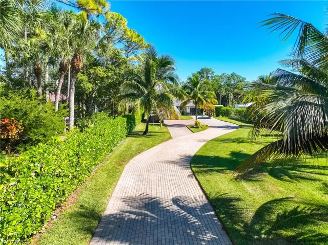 View of property's community with a lawn and decorative driveway