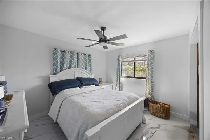 Bedroom featuring marble look tiles and ceiling fan