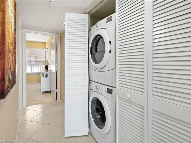 Laundry room featuring stacked washing machine and dryer and light tile patterned flooring