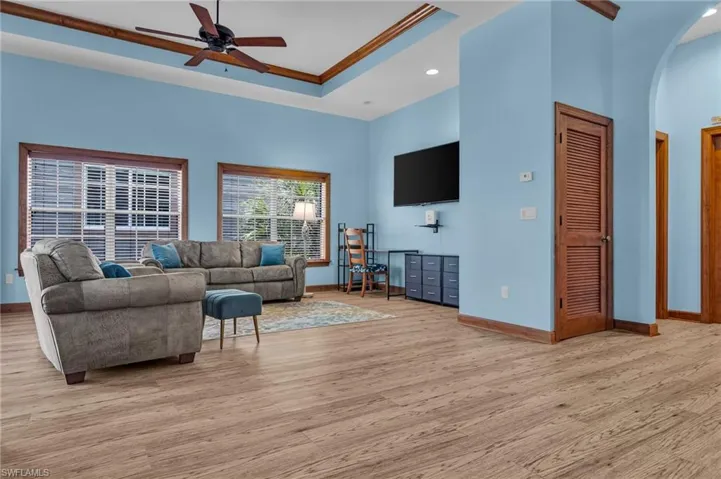 Living room with arched walkways, light wood-style floors, baseboards, and ceiling fan