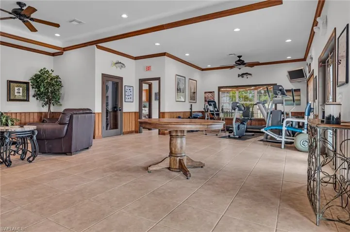 Living area featuring light tile patterned flooring, ceiling fan, a wainscoted wall, visible vents, and recessed lighting