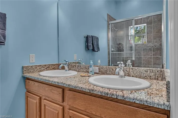 Full bath featuring a sink, double vanity, and a stall shower