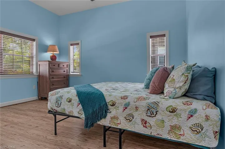 Bedroom with baseboards, wood style finished floors, and multiple windows